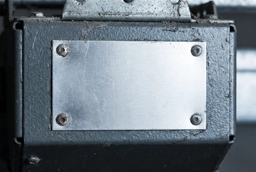 A scratched aluminium data plate riveted to the casing of an old opener motor